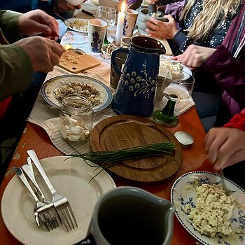 Essen wie die Römer Menschen bereiten an einem gedeckten Tisch mit Kerze und Keramikgeschirr Speisen zu.